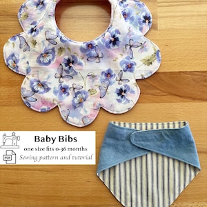 Op de afbeelding: Twee baby slabbetjes. Eén is bloemvormig met een bloemenpatroon van paarse viooltjes en vlinders op een witte achtergrond. De andere is een bandana-stijl met een blauwe denim top en een gestreept patroon.