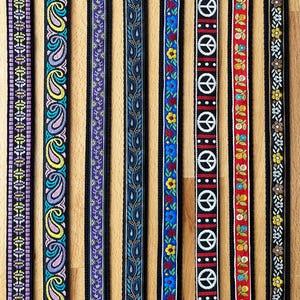May include: Eight vertical fabric ribbons featuring distinct patterns: purple geometric, multi-colored paisley, purple floral, blue paisley, blue floral, white peace signs on black, red floral, and black floral with yellow flowers.