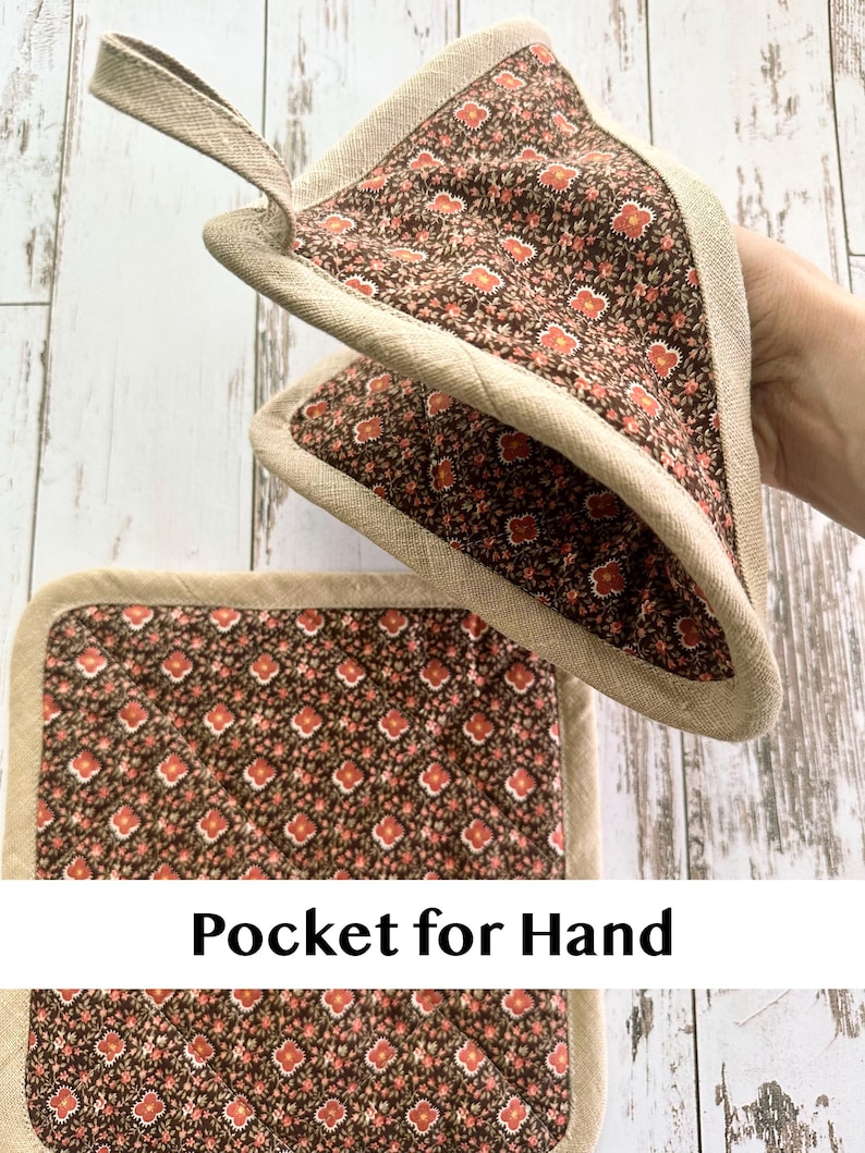 May include: Two brown and red floral print pot holders with a beige trim and a loop for hanging. One pot holder is square, and the other is triangular. The text "Pocket for Hand" is visible on the image.