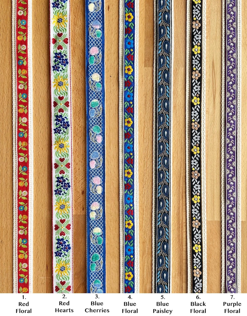 May include: Seven vertical strips of decorative woven ribbon featuring distinct patterns: red floral, red hearts, blue cherries with a grid, blue floral, blue paisley, black floral, and purple floral. Each ribbon has a cream-colored border.