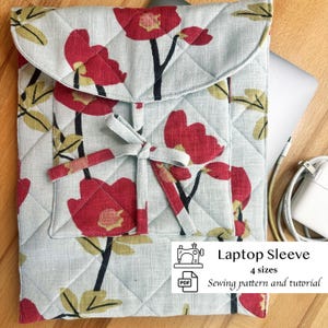 May include: Quilted laptop sleeve with a floral pattern of red flowers and black stems on a light blue background. The sleeve has a flap closure with a tie and a small pocket. The image includes the text "Laptop Sleeve" and "Sewing pattern and tutorial".