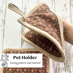 Può includere: Un presina con stampa floreale marrone e rossa con bordo beige e anello per appenderla. Il testo "Pot Holder" e "Sewing pattern and tutorial" è visibile. È un tessuto da cucina.