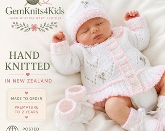 May include: A white hand-knitted baby cardigan with pink trim, matching bonnet, and booties. The set features delicate floral embroidery, eyelet patterns, and white ribbon ties. Text includes GemKnits4Kids, HAND KNITTED IN NEW ZEALAND, and MADE TO ORDER.