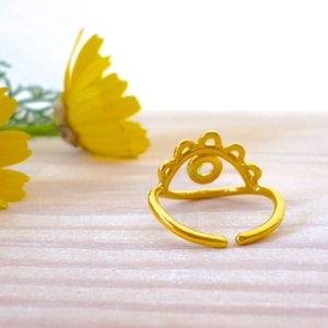 May include: Gold ring with a green stone and a decorative design. The ring is open in the back and has a scalloped edge.