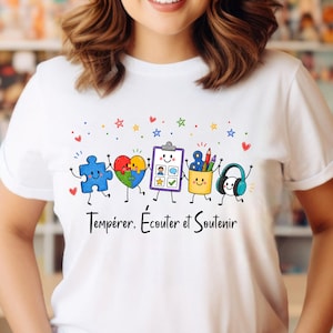 May include: A white t-shirt featuring a colourful graphic of five anthropomorphic items including a blue puzzle piece, a heart, a clipboard, a pencil holder, and headphones, with the text "Tempérer, Écouter et Soutenir" printed below.