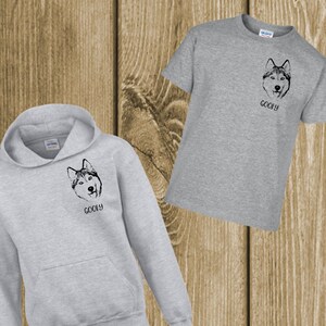 Peut inclure: Un sweat à capuche gris et un t-shirt gris avec une image en noir et blanc d'un chien husky et le mot "Goofy" imprimé dessus.