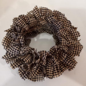 May include: A brown and black gingham fabric wreath. The fabric is frayed and gathered to create a full, round shape.