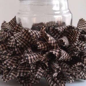 May include: A clear glass jar with a black and white checkered fabric ruffle around the bottom. The fabric is frayed and has a rustic look.