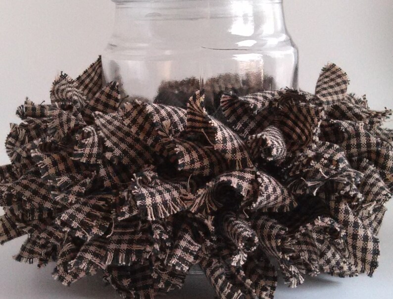 May include: A clear glass jar with a black and white checkered fabric ruffle around the bottom. The fabric is frayed and has a rustic look.