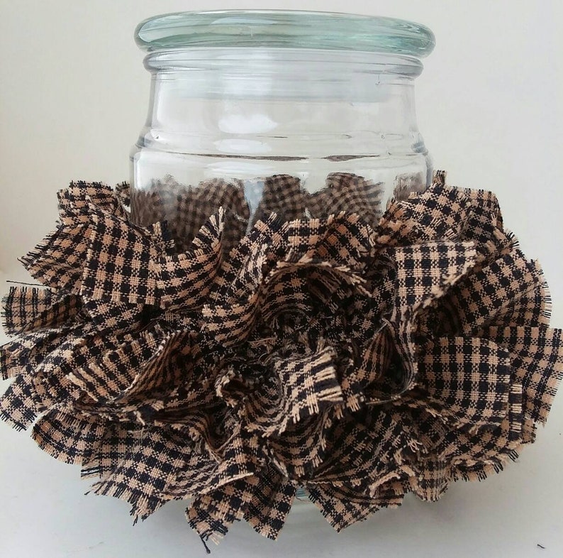 May include: A clear glass jar with a black and tan checkered fabric ruffle around the bottom.
