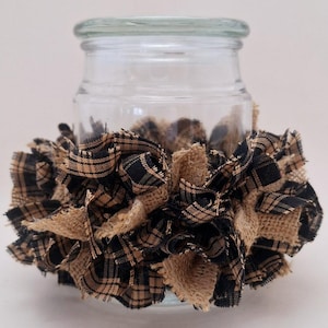 May include: A clear glass jar with a black and tan plaid fabric and burlap ruffle around the bottom.