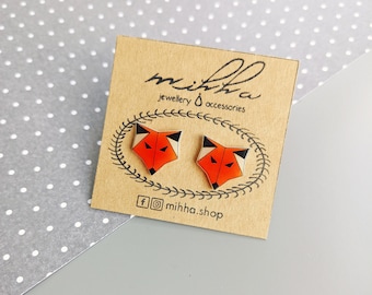 Könnte beinhalten: Ein Paar Fuchs-Ohrringe mit orangefarbenen, schwarzen und weißen geometrischen Mustern. Die Ohrringe werden auf einer braunen Karte mit dem Text "miihha jewellery & accessories" und "miihha.shop" präsentiert.