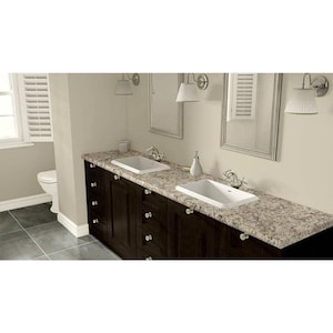 May include: A double vanity cabinet with dark brown wood finish and a speckled beige granite countertop. It features two rectangular white ceramic sinks, chrome faucets, and silver knobs. Two rectangular mirrors hang above the sinks with wall-mounted lamps on either side.