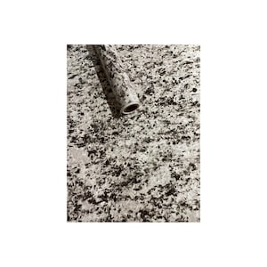 May include: A roll of white and black granite-patterned contact paper. The paper is rolled up and the end of the roll is visible.