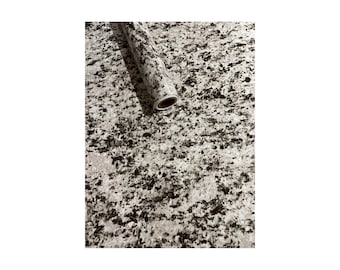 May include: A roll of white and black granite-patterned contact paper. The paper is rolled up and the end of the roll is visible.