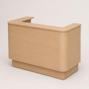 May include: A light wood reception desk featuring a U-shaped top surface with rounded corners and a solid front panel. The structure is supported by a recessed base, showcasing a consistent light oak grain finish throughout the entire unit.