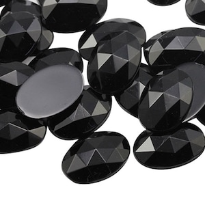 May include: A group of black oval-shaped rhinestones with a faceted design.