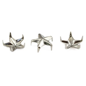May include: Three silver star-shaped metal studs with five points each. The studs are designed for use in crafts and DIY projects.