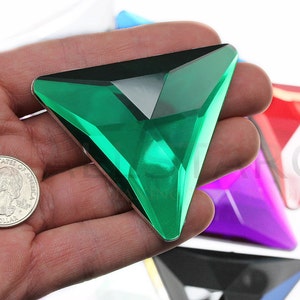 May include: A green triangular crystal with a reflective surface. The crystal is about the size of a US quarter.