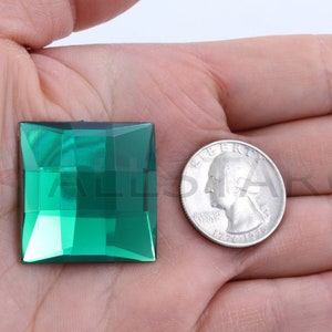 Op de afbeelding: Een vierkante smaragdgroene glazen edelsteen, ongeveer ter grootte van een Amerikaanse kwart.