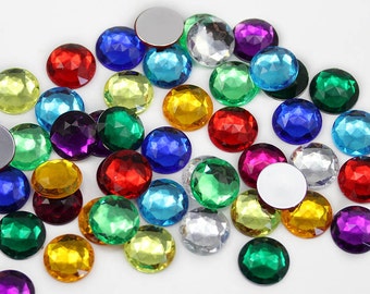 May include: Assortment of colourful round rhinestones with faceted edges. The rhinestones are various colours, including red, blue, green, yellow, purple, and clear.