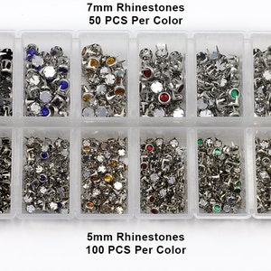 May include: A clear plastic organiser filled with various colours of rhinestones. The top row contains 7mm rhinestones, 50 pieces per colour, and the bottom row contains 5mm rhinestones, 100 pieces per colour. The rhinestones are silver-coloured with different coloured gems.