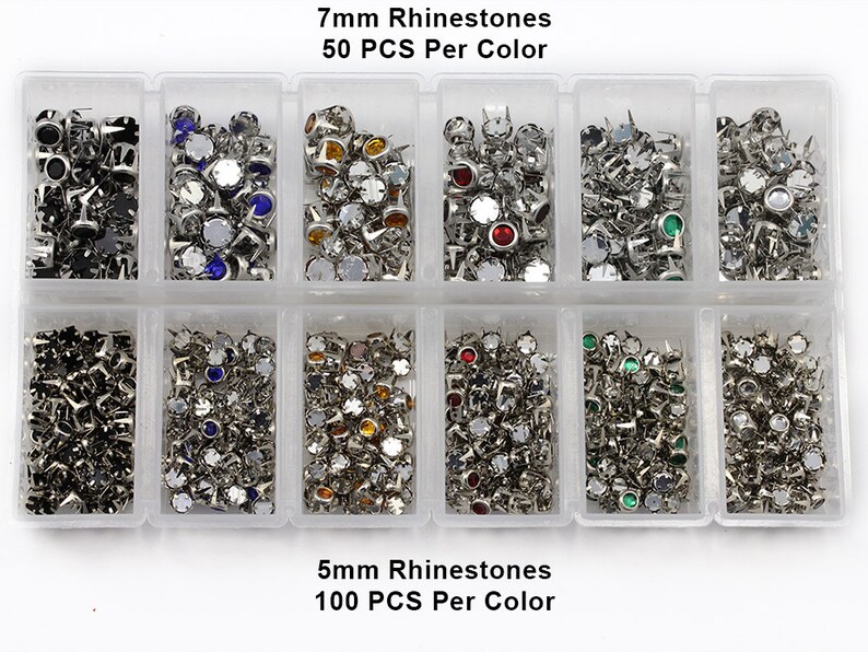 May include: A clear plastic organiser filled with various colours of rhinestones. The top row contains 7mm rhinestones, 50 pieces per colour, and the bottom row contains 5mm rhinestones, 100 pieces per colour. The rhinestones are silver-coloured with different coloured gems.