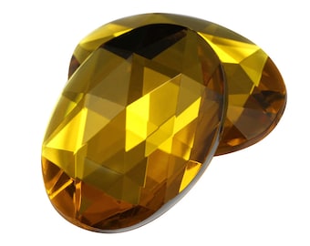 May include: Two oval-shaped, faceted glass gems in a golden amber color.