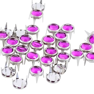 May include: A scattering of silver-toned metal studs with purple rhinestones. The studs have a pointed base and are designed for attaching to fabric.