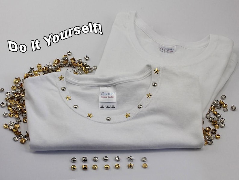 May include: Two white t-shirts, one folded and embellished with silver and gold star and round studs around the neckline. Scattered studs in various shapes and colors are displayed. The text "Do It Yourself!" is in the upper left corner.