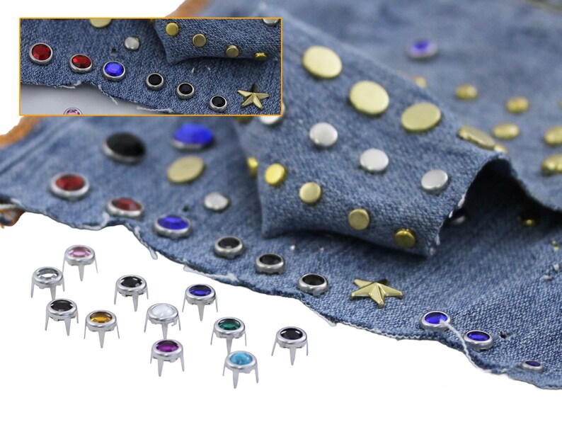May include: Close-up of denim fabric decorated with assorted metal and jewel-toned studs. The studs include gold, silver, black, red, blue, and clear gems, plus a gold star-shaped stud. Several individual studs are also shown.