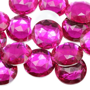 Peut inclure: Gros plan sur un groupe de gemmes rondes en plastique facettées de couleur rose. Les gemmes sont éparpillées sur une surface blanche.