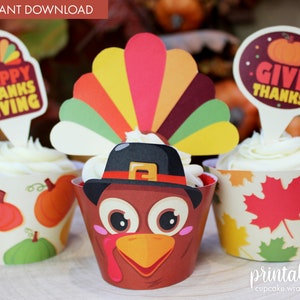 May include: Printable cupcake wrappers featuring a Thanksgiving turkey design with a brown hat, orange beak, and large eyes. The wrappers are decorated with pumpkins and leaves. There are also printable cupcake toppers with the text "Happy Thanksgiving" and "Give Thanks".