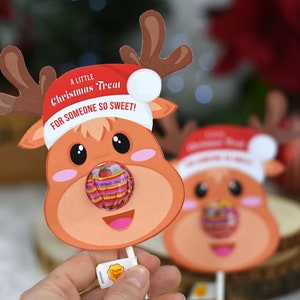 Puede incluir: Un recorte de cabeza de reno rojo y blanco con una piruleta pegada en la nariz. El reno lleva un gorro de Pap&aacute; Noel rojo y el texto "A Little Christmas Treat For Someone So Sweet!" est&aacute; impreso en el recorte.
