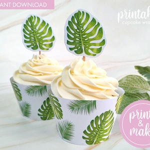 May include: Printable cupcake wrappers with a tropical leaf design. The wrappers are white with green leaves and feature a monstera leaf design. The wrappers are topped with cupcakes and monstera leaf cupcake toppers.