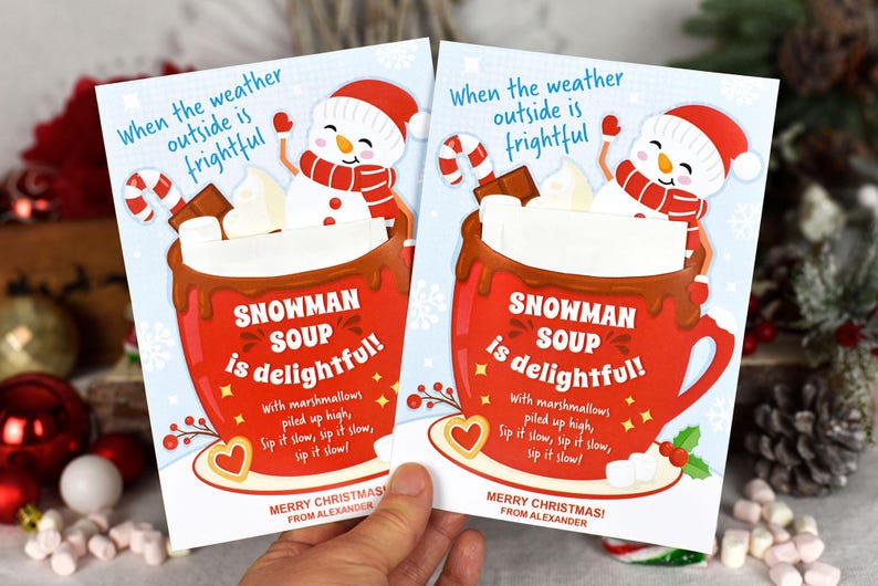 Puede incluir: Dos tarjetas de Navidad con un mu&ntilde;eco de nieve en una taza roja de chocolate caliente con malvaviscos. El texto en las tarjetas dice "Cuando el clima afuera es espantoso, &iexcl;la sopa de mu&ntilde;eco de nieve es deliciosa!" con malvaviscos apilados en alto, &iexcl;b&eacute;belo despacio, b&eacute;belo despacio, b&eacute;belo despacio! &iexcl;Feliz Navidad! De parte de Alexander.
