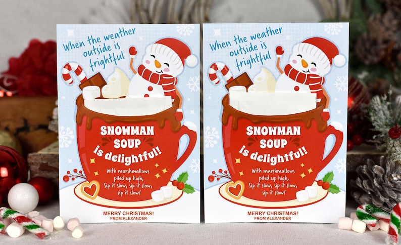 Puede incluir: Dos tarjetas de Navidad con un mu&ntilde;eco de nieve en una taza roja de chocolate caliente con malvaviscos. El texto de la tarjeta dice "Cuando el clima afuera es espantoso, &iexcl;la sopa de mu&ntilde;eco de nieve es deliciosa!" con malvaviscos apilados alto, b&eacute;belo despacio, b&eacute;belo despacio, b&eacute;belo despacio! &iexcl;Feliz Navidad! De parte de Alexander.