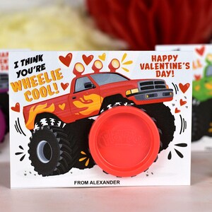 May include: A Valentine's Day card featuring a red monster truck with the text "I think you're wheelie cool!" and "Happy Valentine's Day!" The card has a red play dough container attached to it.