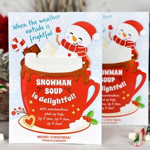 Puede incluir: Una tarjeta de Navidad roja y blanca con un mu&ntilde;eco de nieve en una taza de chocolate caliente. La tarjeta dice "Cuando el clima afuera es terrible, la sopa de mu&ntilde;eco de nieve es deliciosa!" con malvaviscos apilados en alto.  "Beba despacio, beba despacio, beba despacio!" &iexcl;Feliz Navidad! De parte de Alexander.