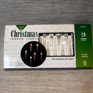 May include: A box of Everglow Christmas indoor icicle lights. The box is white and green with the words "Christmas Indoor Lights" in large letters. A circular graphic shows six icicle lights. The box contains 20 lights.