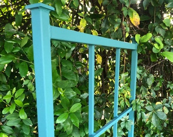 May include: A teal blue metal trellis with a square design. The trellis is made of sturdy metal bars and is perfect for supporting climbing plants.