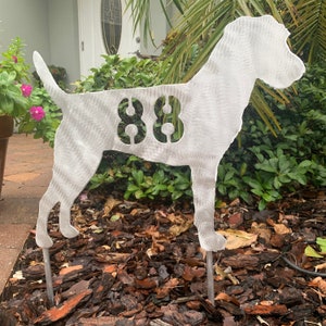 May include: A white metal silhouette of a dog with the number 88 cut out of the body. The dog is standing on a bed of brown mulch.