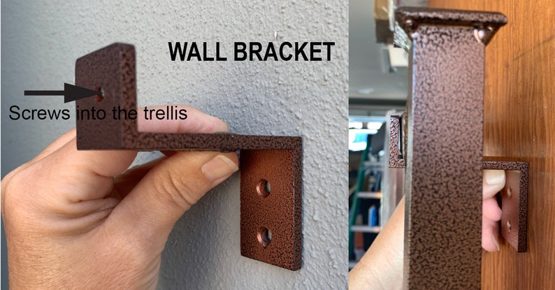 May include: A close-up of a brown metal wall bracket with two holes. The bracket is attached to a wall and has a screw going into the trellis. The text "WALL BRACKET" is visible above the bracket.