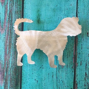 May include: A metal silhouette of a dog, cut out in the shape of a terrier, against a turquoise wooden background.