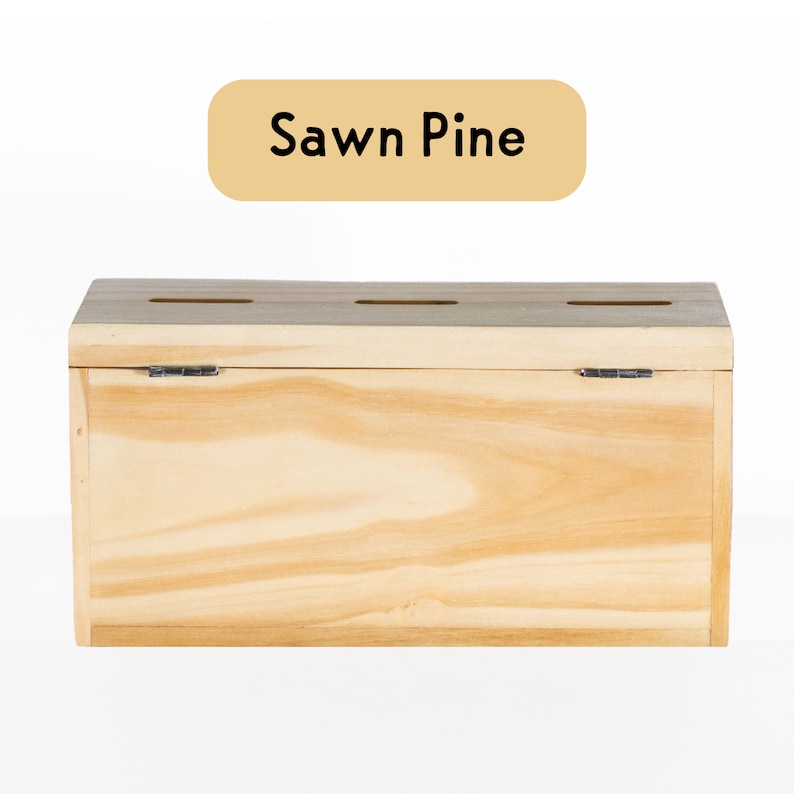 Puede incluir: Una caja de madera con tapa con bisagras y tres ranuras en la parte superior. La caja est&aacute; hecha de madera de pino aserrada y tiene un acabado de madera natural. El texto "Sawn Pine" est&aacute; impreso en una etiqueta amarilla.