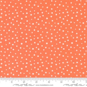May include: A vibrant orange cotton fabric featuring a dense, scattered pattern of small white polka dots of varying sizes. A white measuring tape is visible along the bottom edge, showing a scale of 7 inches for the width of the fabric.