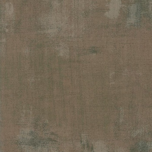 Może przedstawiać: Zbliżenie na teksturowaną tkaninę o postarzanym wyglądzie. Paleta kolorów zdominowana jest przez odcienie brązu i szarości, z subtelnymi nutami zieleni. Tkanina ma zużytą, vintage estetykę.