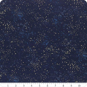 May include: A dark navy blue fabric featuring a speckled pattern of small, scattered dots in pale yellow and bright blue. A white ruler with black markings is visible along the bottom edge, showing a measurement scale of 10 inches.