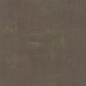 Pode incluir: Close-up de um tecido texturizado com aparência desgastada. O tecido é principalmente marrom suave, com sutis destaques verdes e pinceladas visíveis, criando uma estética vintage ou rústica.