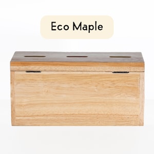 Puede incluir: Una caja de madera con tapa abatible y tres ranuras en la parte superior. La caja est&aacute; hecha de madera de arce ecol&oacute;gica y tiene un acabado de madera natural. El texto "Eco Maple" est&aacute; impreso en una etiqueta encima de la caja.